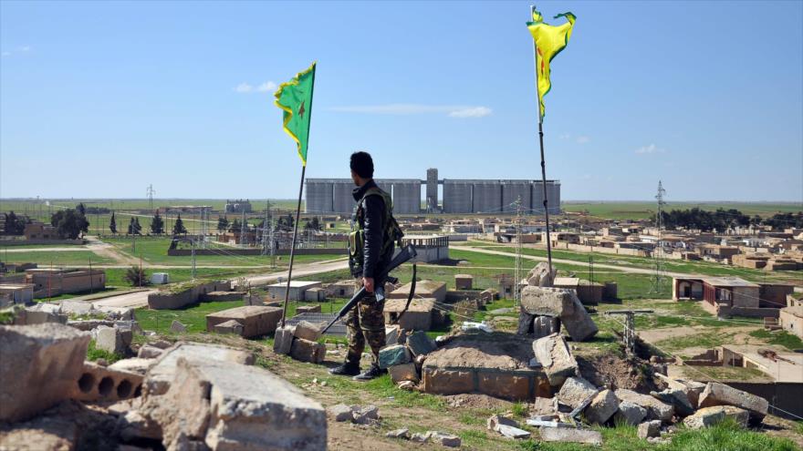 Un miembro del Partido de la Unión Democrática (PYD, en kurdo) se encuentra en la cima de una colina con vistas a un pueblo de la ciudad Qamishli, en el noreste de Siria en la frontera con Turquía.