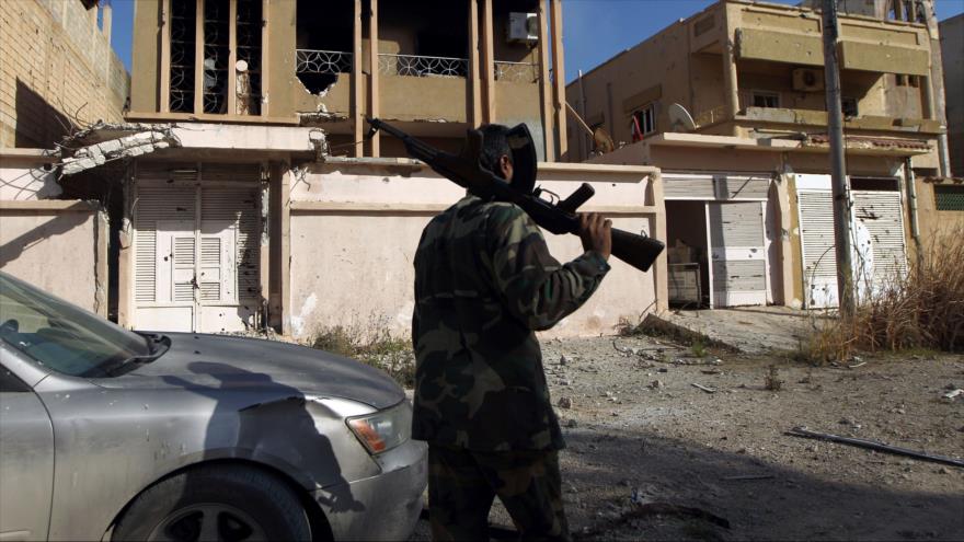 Un combatiente leal al gobierno reconocido internacionalmente de Libia camina a lo largo de una calle en Bengasi tras tomar el control del centro de la ciudad nororiental de las manos de terroristas, 23 de febrero de 2016.