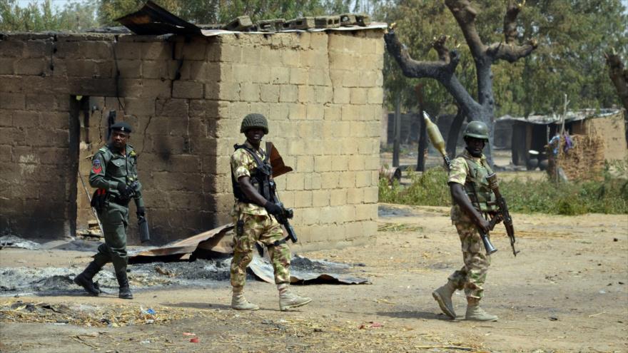 Los soldados y policías nigerinos a pie delante de una casa quemada por el ataque del grupo terrorista Boko Haram en la localidad de Dalori, a unos 12 kilómetros de la ciudad nororiental Maiduguri, 4 febrero de 2016.