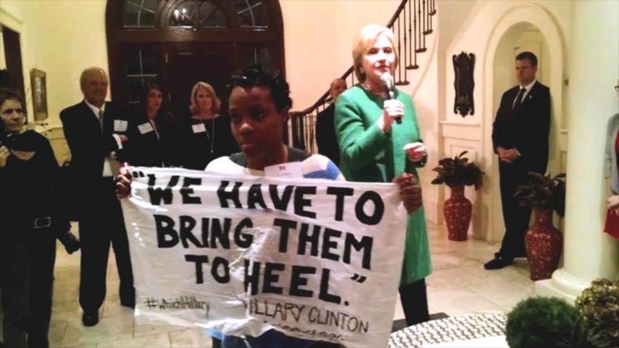 Una activista del movimiento nacional Black Lives Matter con un cartel que dice: “Debemos llamarlos al orden”, interrumpe a la candidata presidencial demócrata Hillary Clinton durante un evento de recaudación de fondos en Charleston (Carolina del Sur, en el sudeste de EE. UU.), 24 de febrero de 2015