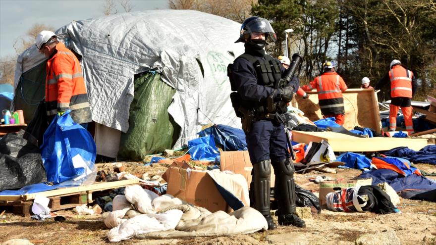 Un policía vigila mientras equipos de demolición comienzan a desmantelar la parte sur del campamento de migrantes llamado la "jungla" de Calais (norte de Francia), 29 de febrero de 2016.