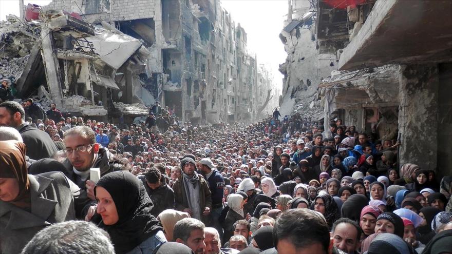 Cientos de personas abandonan el bombardeado campamento de refugiados de Yarmuk, en el sur de Siria.
