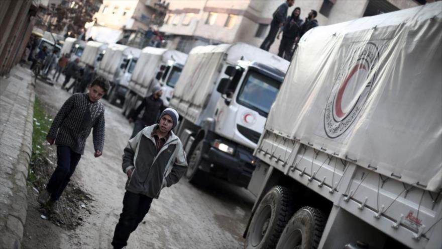 Un convoy de la Media Luna Roja con ayuda humanitaria, en cooperación con la ONU, llega a una zona controlada por grupos terroristas, en las afueras de la capital siria de Damasco, 23 de febrero de 2016.