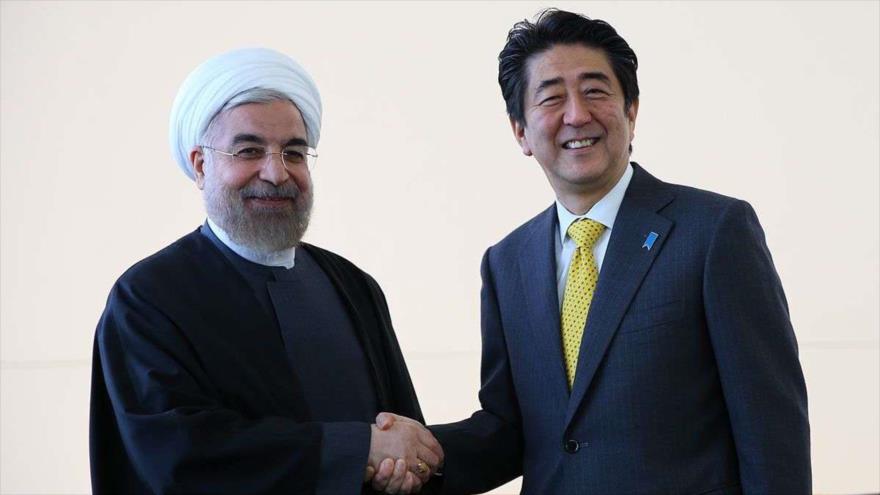 El presidente iraní, Hasan Rohani (izda.), y el primer ministro de Japón, Shinzo Abe, se estrechan la mano durante un encuentro.