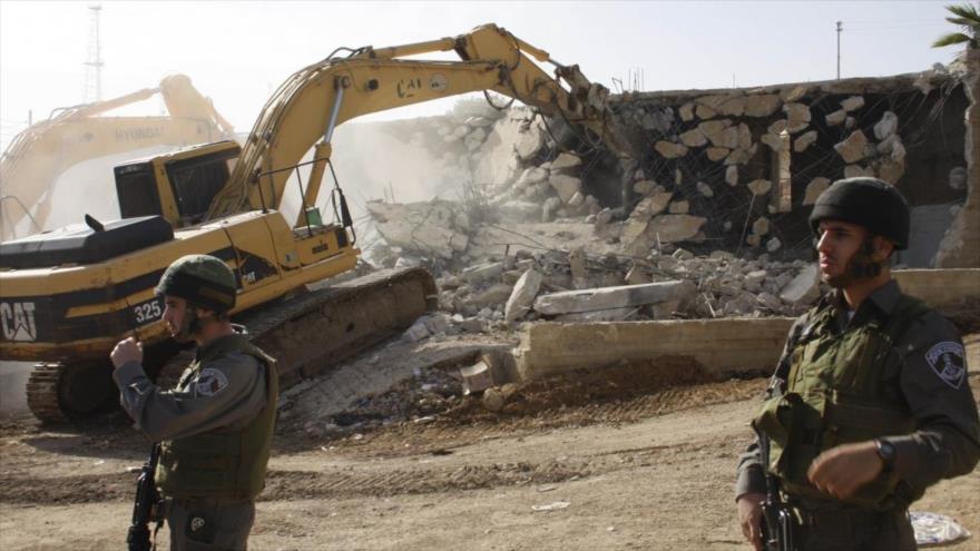 Una excavadora, acompañada por soldados israelíes, destruye una casa palestina en la ocupada Cisjordania.