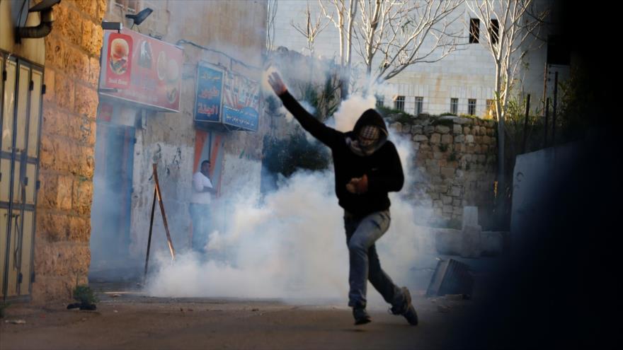 Un manifestante palestino arroja una granada de gas lacrimógeno durante enfrentamientos con las fuerzas de seguridad israelíes en la ocupada Cisjordania, 11 de marzo de 2016.