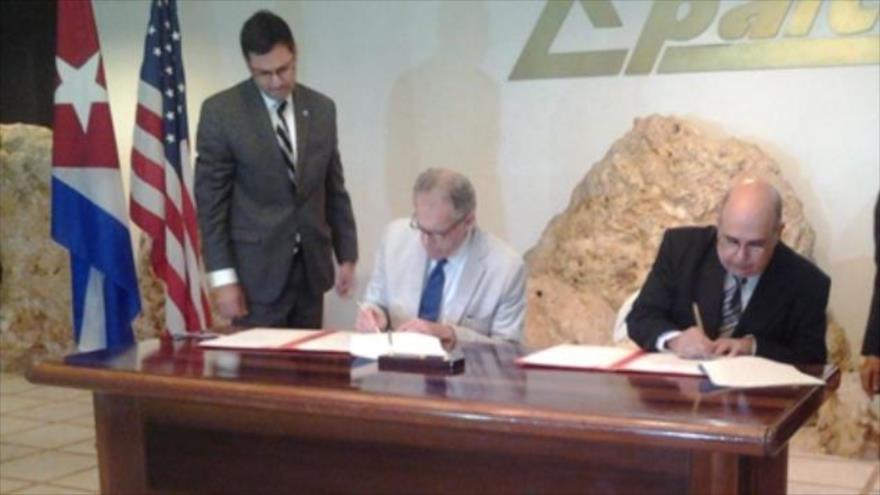 El encargado de negocios de la embajada de Estados Unidos en La Habana (capital de Cuba), Jeffrey DeLaurentis (izda.) y el jefe de la Oficina Nacional de Hidrografía y Geodesia (ONHG), Cándido Regalado Gómez (drcha.), firman un acuerdo sobre seguridad marítima, 18 de marzo de 2016.