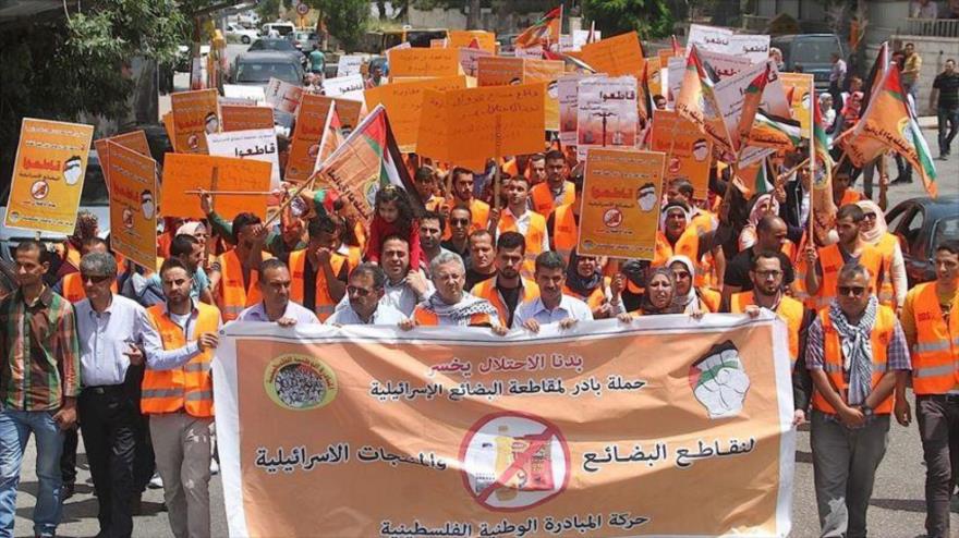 Manifestantes palestinos sostienen banderas nacionales y pancartas en las que se lee en árabe: "boicotear los productos israelíes, la campaña de iniciativa nacional palestina", durante una manifestación pidiendo el boicot a los productos israelíes, en la ciudad ocupada de Ramalá, 27 de Febrero 2016.