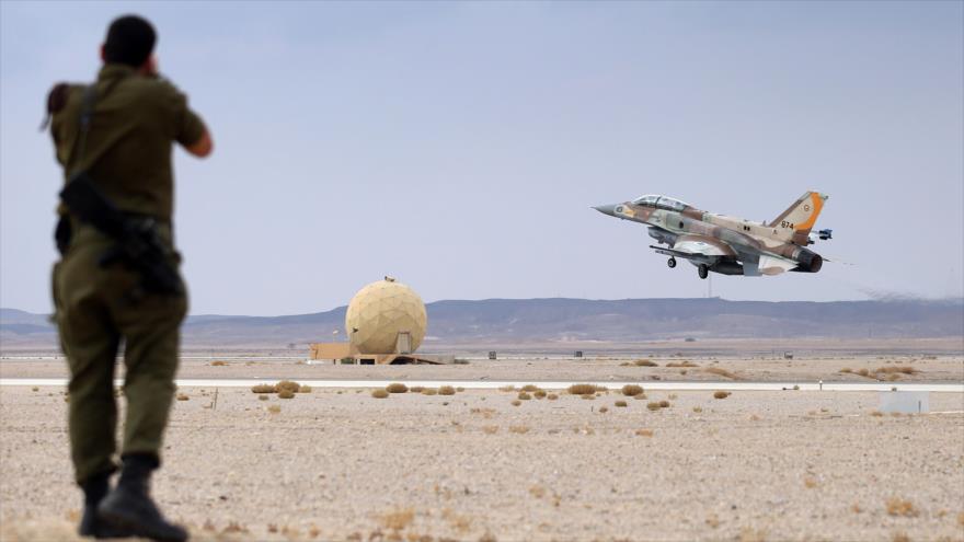 Soldado israelí protege sus oídos mientras despega un caza F-16 de la aviación militar de este régimen.