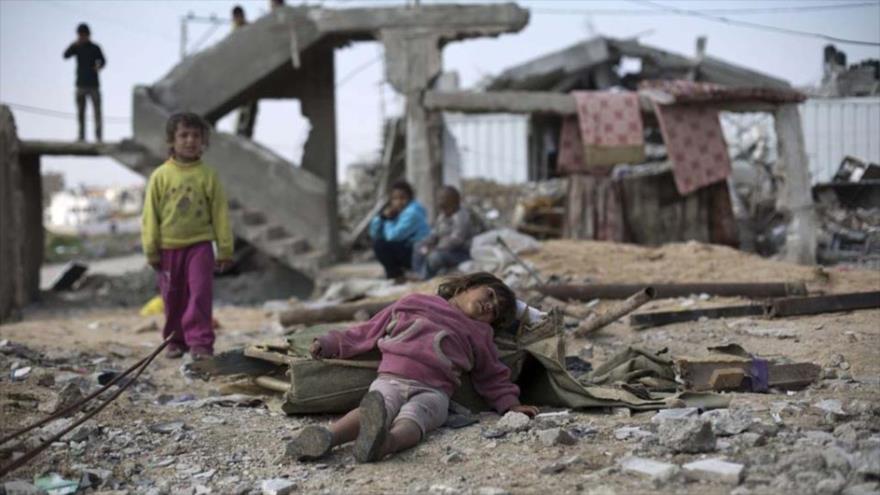 Una niña yemení descansa entre los edificios en ruinas por la agresión de Arabia Saudí contra su país.
