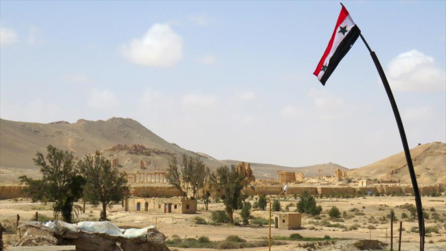 La bandera de Siria ondea por encima de la antigua ciudad de Palmira, después de que las tropas sirias liberaran la ciudad de manos del grupo terrorista EIIL (Daesh, en árabe), 27 de marzo de 2016.