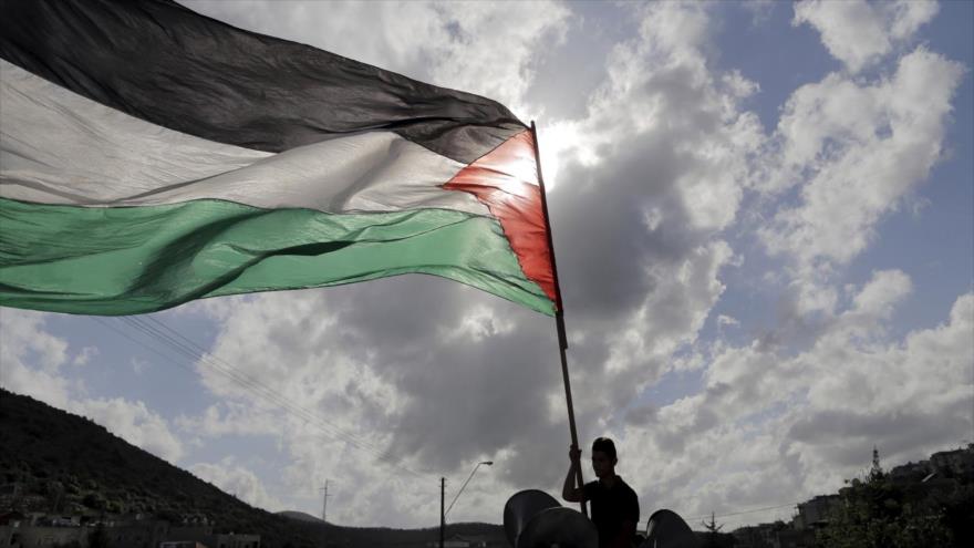 Un hombre ondea la bandera de Palestina.
