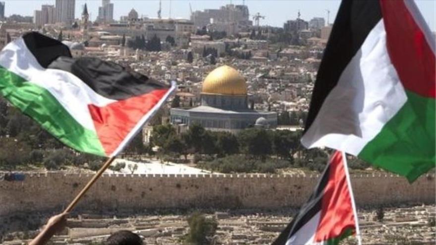 Palestinos hondean su bandera nacional en la ciudad de Al-Quds.