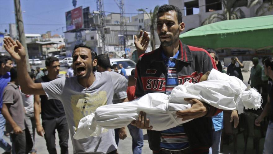 Un palestino sostiene el cadáver de un niño asesinado por soldados israelíes.