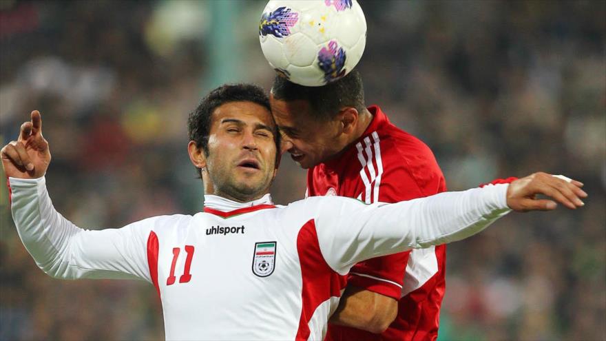 El futbolista iraní Mehrdad Oladi (izda.) lucha por la pelota con un jugador de Baréin.