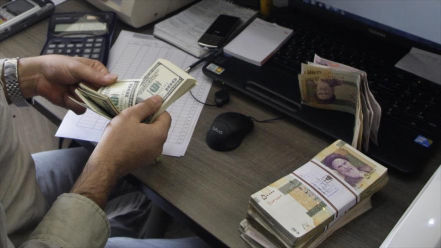La foto muestra billetes en rial y dólar.

