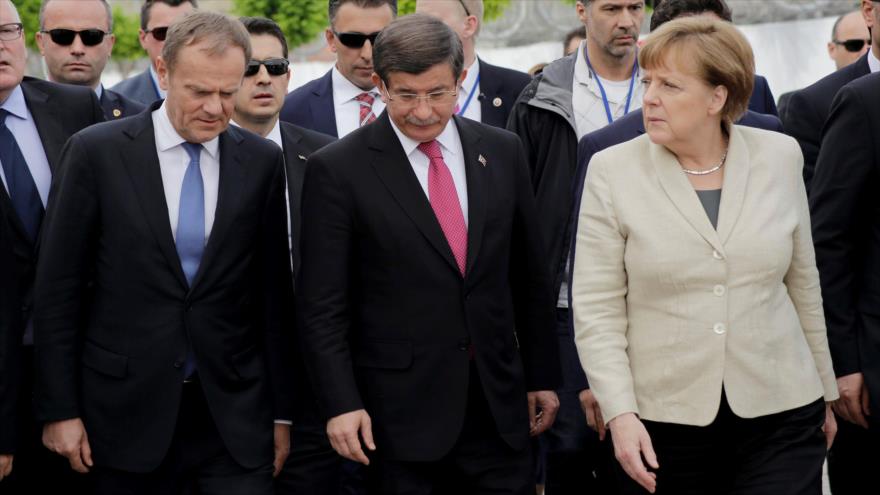 El presidente del Consejo Europeo, Donald Tusk (izda.), la canciller alemana, Angela Merkel (dcha.), y el primer ministro turco, Ahmed Davutoglu, visitan un campo de refugiados en la localidad de Gaziantep (sureste de Turquía), fronteriza con Siria, 23 de abril de 2016.
