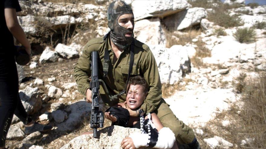 Un soldado israelí detiene a un niño palestino.