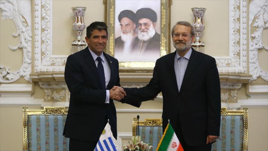 El presidente del Parlamento iraní, Ali Lariyani (dcha.), y el presidente de la Cámara de Senadores y de la Asamblea General de Uruguay, Raúl Sendic, se estrechan la mano durante una reunión en Teherán, capital persa, 25 de abril de 2016.