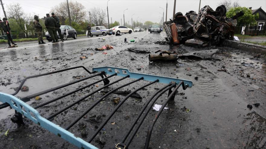 Los expertos examinan el sitio junto a un coche destruido por los bombardeos en un puesto de control de independentistas en la ciudad de Olenivka en Ucrania, 27 de abril de 2016.
