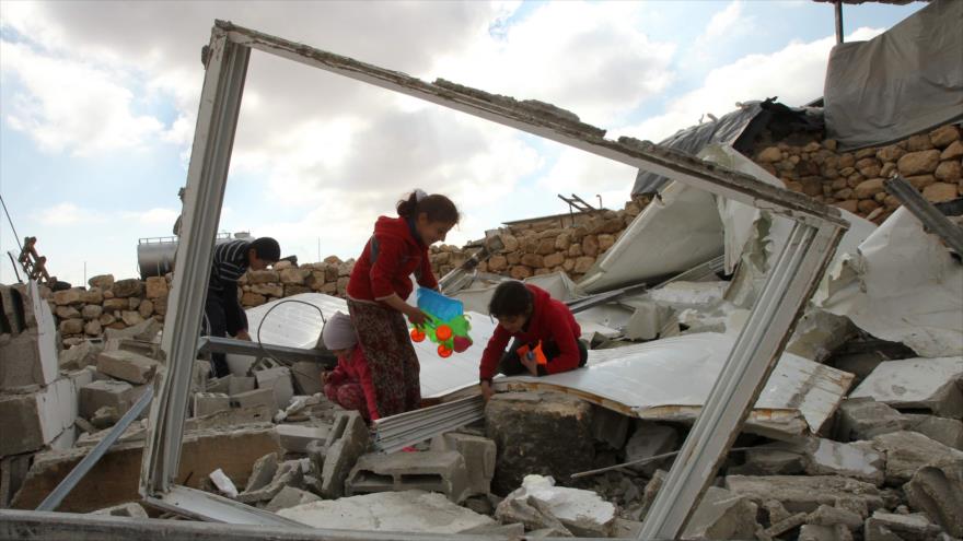 
Niños palestinos buscando sus pertenencias entre los escombros de su casa demolida por el régimen de Israel en la Cisjordania ocupada.
