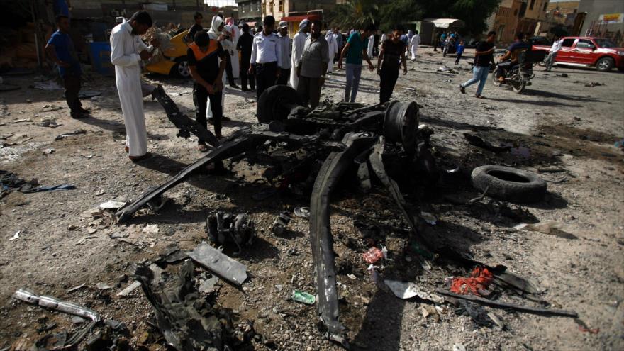 Ciudadanos iraquíes reunidos en el sitio de un atentado con coche bomba en el sur de Irak.