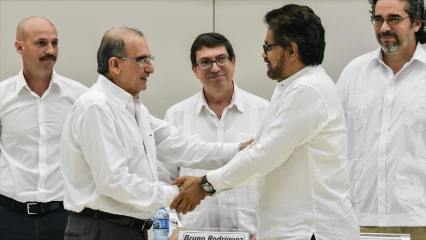 El máximo jefe de la delegación gubernamental para los diálogos de paz, Humberto de la Calle (izda.), y el jefe del equipo negociador de las FARC, Iván Márquez, se dan la mano tras firmar un acuerdo sobre las víctimas del conflicto armado, 15 de diciembre de 2015.