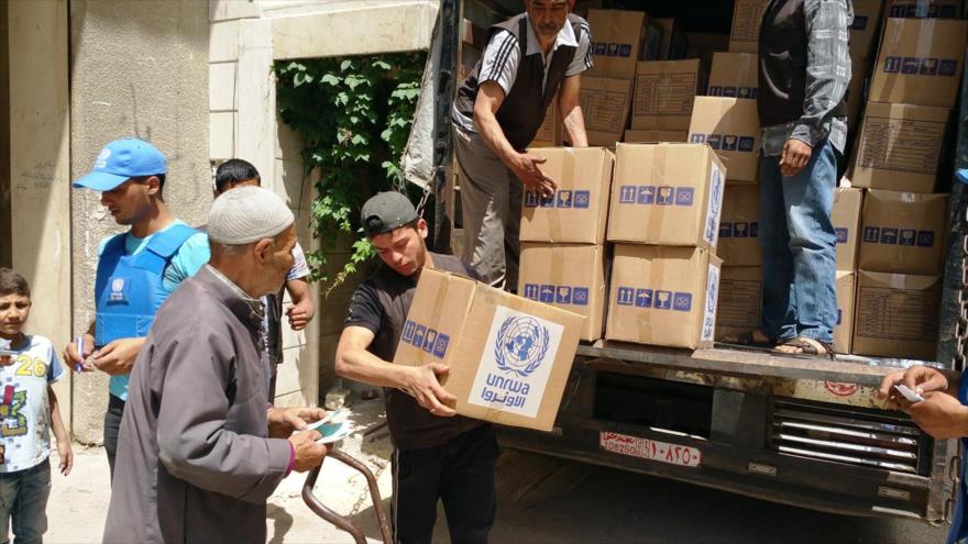 Palestinos en Al-Yarmuk reciben ayudas humanitarias distribuidas por la UNRWA.
