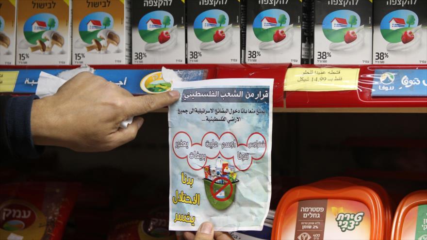 Un activista palestino muestra una pancarta que pide el boicot de productos israelíes.