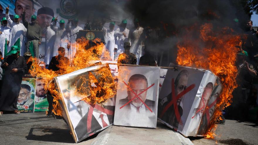 Militantes de HAMAS queman pancartas con las imágenes de Lieberman durante una marcha en la Ciudad de Gaza, 20 de mayo de 2016.