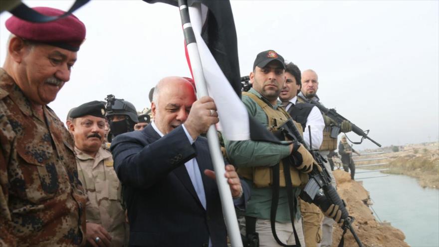 El primer ministro de Irak, Haidar al-Abadi, iza la bandera del país en la ciudad de Ramadi, tras su liberación de manos de Daesh, diciembre de 2015.