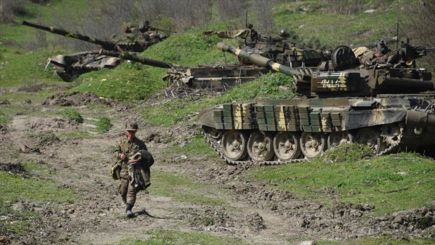 Un soldado de la región de Nagorno-Karabaj pasa delante de tanques desplegados a causa del conflicto con Azerbaiyán.