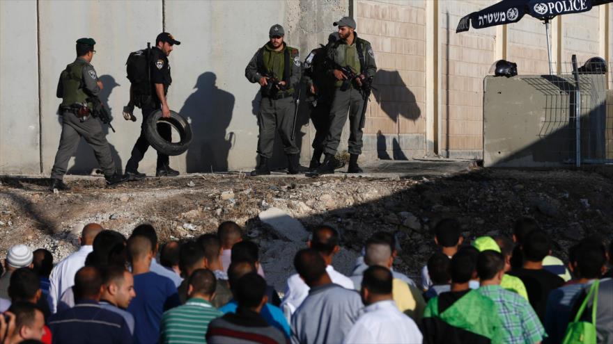 Fuerzas israelíes montan guardia mientras los palestinos esperan cruzar el puesto de control israelí en Qalandia, para ir a la mezquita Al-Aqsa, en la ciudad de Al-Quds (Jerusalén), 10 de junio de 2016.