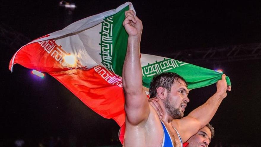 Komeil Qasemi, de la categoría de 125 kg, ondea la bandera de la República Islámica de Irán como campeona de la Copa Mundial de Los Ángeles (2016-EE.UU.).