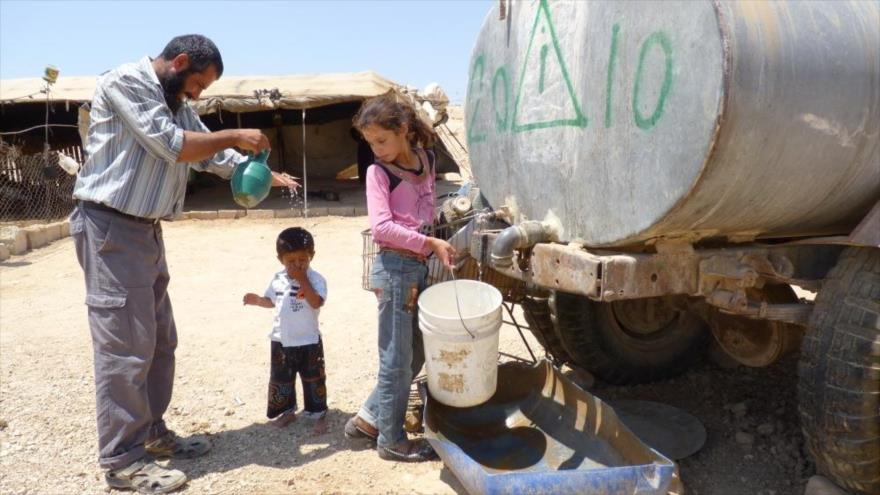 Residentes palestinos llenan de agua sus cubos en Cisjordania.