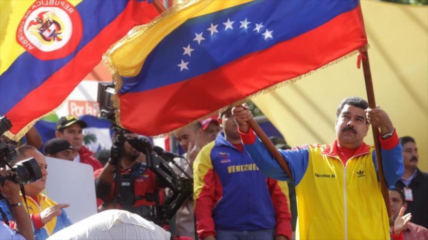 El presidente de Venezuela, Nicolás Maduro, levanta dos banderas durante una marcha a favor de la continuidad de su mandato.