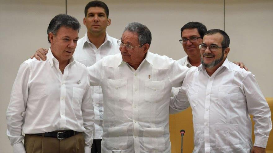 El presidente cubano, Raúl Castro (centro), abraza a su par colombiano, Juan Manuel Santos (izqda.), y al líder de las FARC, Timoleón Jiménez, alias Timochenko (dcha.).