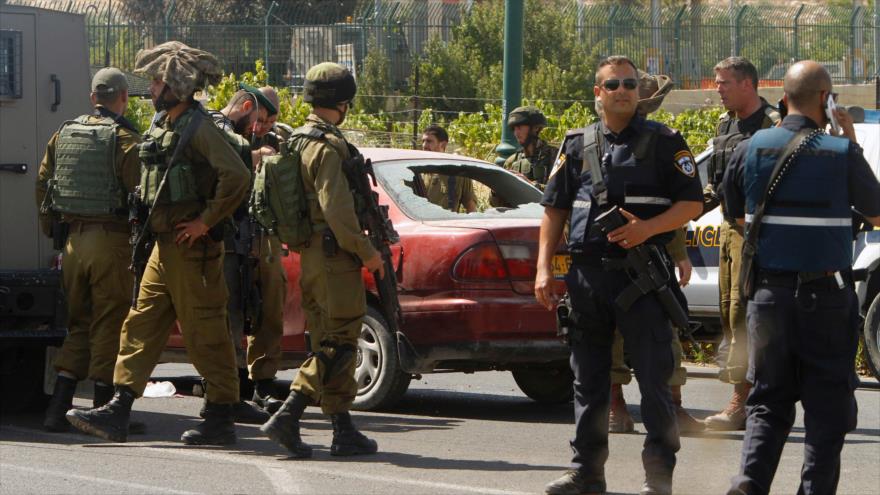 Fuerzas de seguridad israelíes congregados en el lugar, donde mataron a una mujer palestina en Al-Jalil (Hebrón), 24 de junio de 2016.