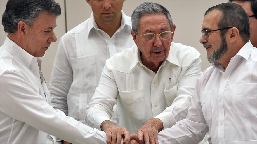 El presidente cubano, Raúl Castro (centro), mantiene las manos de su par colombiano, Juan Manuel Santos (izqda.), y del líder de las FARC, Timoleón Jiménez, alias Timochenko (dcha.).