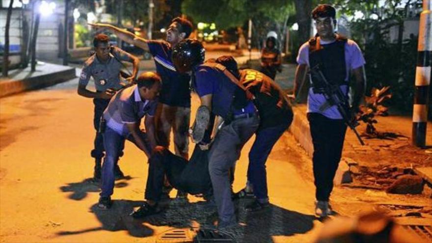 Varias personas ayudan a un herido en un tiroteo en un restaurante en una zona diplomática en la capital de Bangladés, Daka, 1 de julio de 2016.