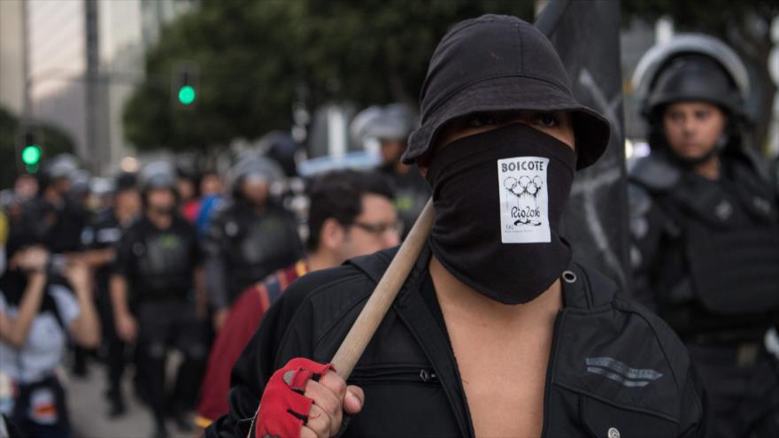 Un miembro de black bloc muestra una pegatina que llama a boicotear los Juegos Olímpicos Río 2016 durante una manifestación en la misma ciudad brasileña, 6 de julio de 2016.