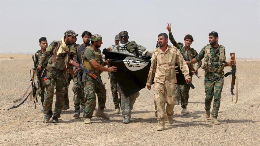 Fuerzas de seguridad iraquíes posan con una bandera de EIIL, tras una victoria contra el grupo terrorista.