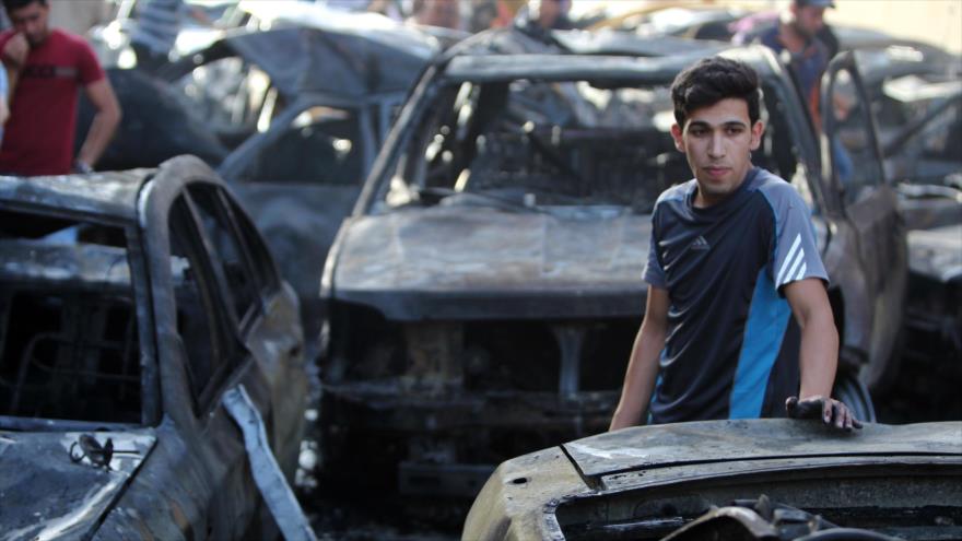 Un hombre iraquí mira los restos de los vehículos destruidos por un coche bomba en Bagdad.