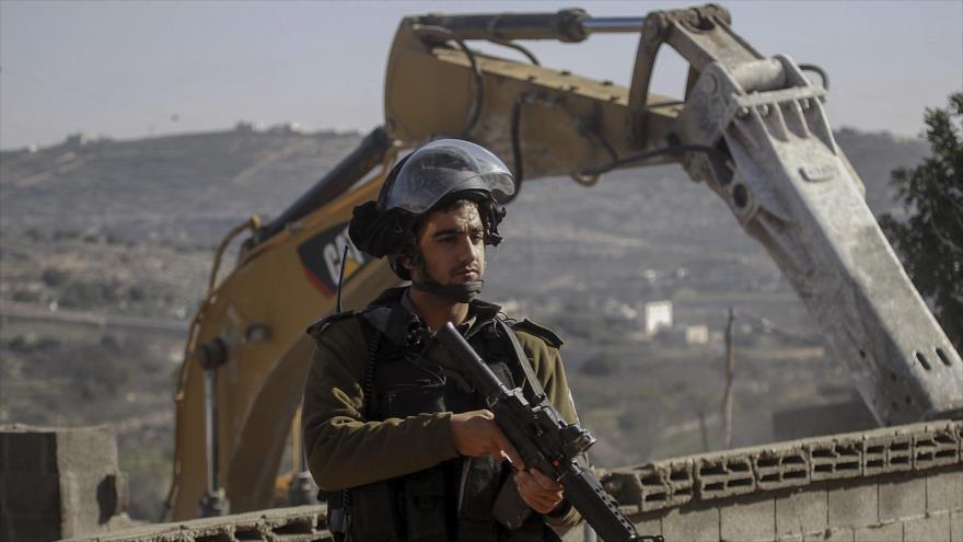 Un soldado israelí hace guardia durante las tareas de construcción de asentamientos ilegales israelíes en los territorios palestinos.