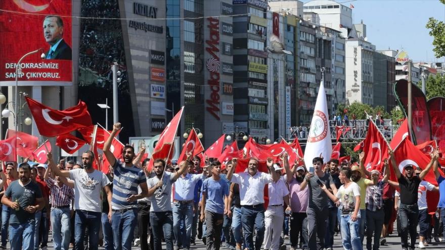 Ciudadanos turcos en Ankara, la capital, marchan desde la plaza Kizilay con destino al edificio del Estado Mayor de las Fuerzas Armadas en protesta por el intento de golpe militar, mientras la imagen del presidente turco, Recep Tayyip Erdogan, aparece en un cartel, 16 de julio de 2016.