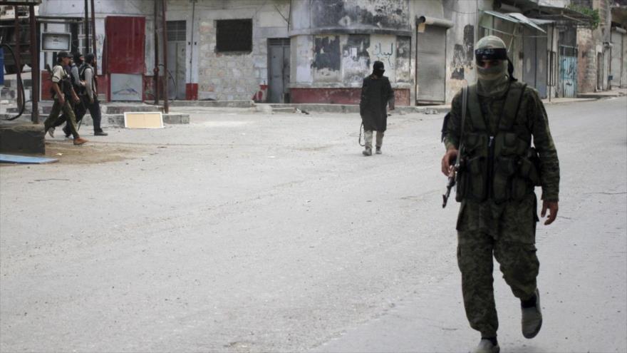Miembros del grupo terrorista Frente Al-Nusra, rama siria de Al-Qaeda, caminan en las calles de la ciudad de Ariha, noroeste de Siria.