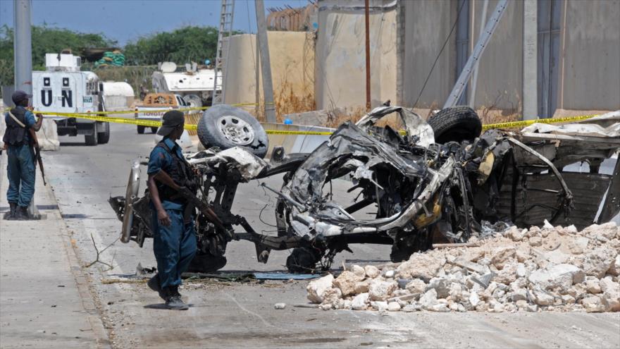 Soldados somalíes cerca de los restos del coche bomba explotado fuera de la base de la Unión Africana (UA), adyacente al aeropuerto de la capital de Somalia, Mogadiscio, 26 de julio de 2016.