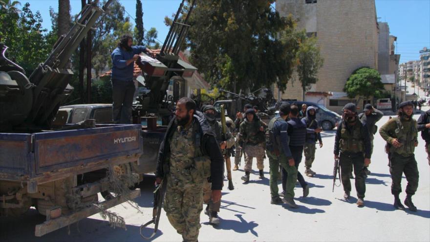 Integrantes de Frente al-Nusra a pie con sus armas en la ciudad de Jisr al-Shughour en la provincial de Idlib, Siria.