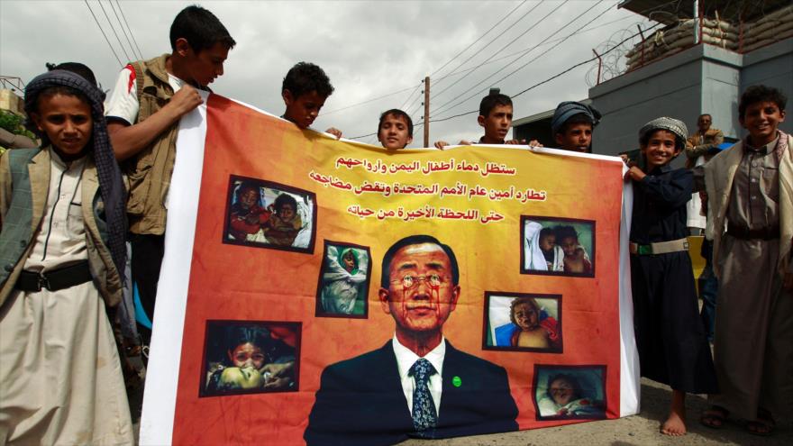 Niños yemeníes sostienen un cartel con la imagen del secretario general de la ONU, Ban Ki-Moon, durante una protesta en Saná, la capital, contra la retirada de Arabia Saudí de la lista negra del organismo, 16 de junio de 2016. 