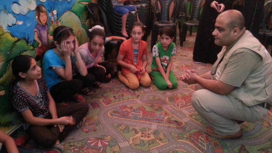 Mohamad Halabi, responsable de la oenegé estadounidense World Vision en Gaza, habla con unos niños palestinos.